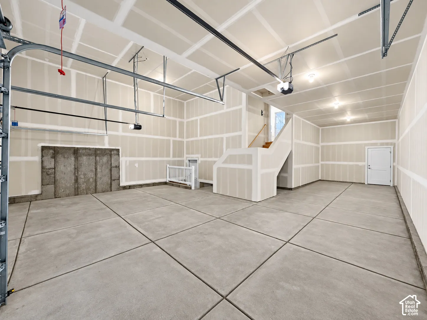Concrete flooring, exposed block foundation, staircase with wood-finish treads, interior door, and garage door track system