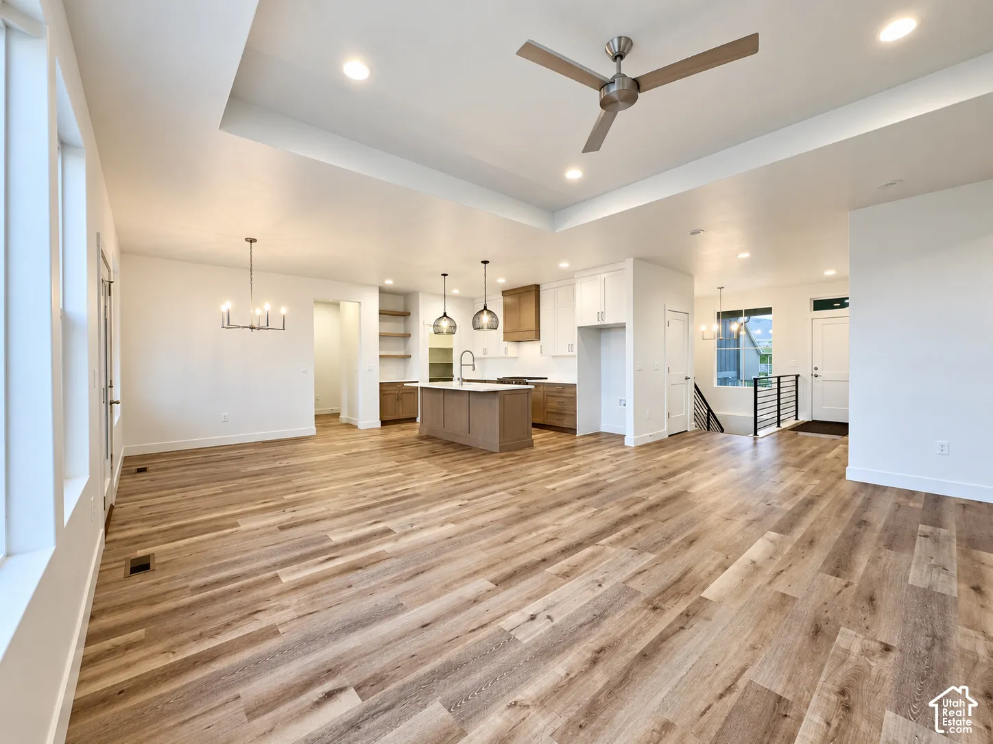Spacious open concept interior with wood-finish flooring, a contemporary kitchen island, recessed lighting, and a modern ceiling fan