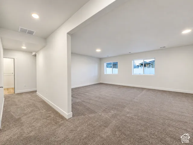 Expansive room featuring recessed lighting, light-toned carpeting, white walls, and multiple windows
