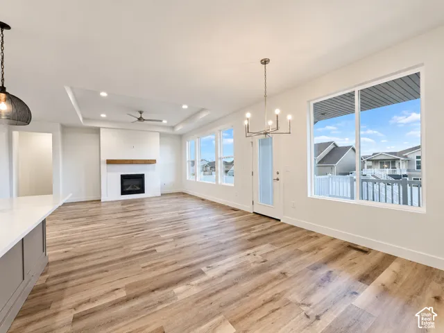 Spacious interior featuring wood-finish flooring, a contemporary fireplace with a wood mantle, a tray ceiling with recessed lighting, and multiple windows