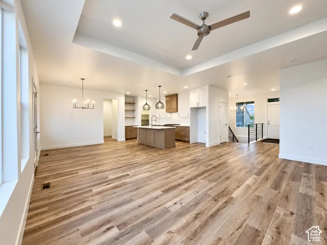 Spacious open concept interior with wood-finish flooring, a contemporary kitchen island, recessed lighting, and a modern ceiling fan