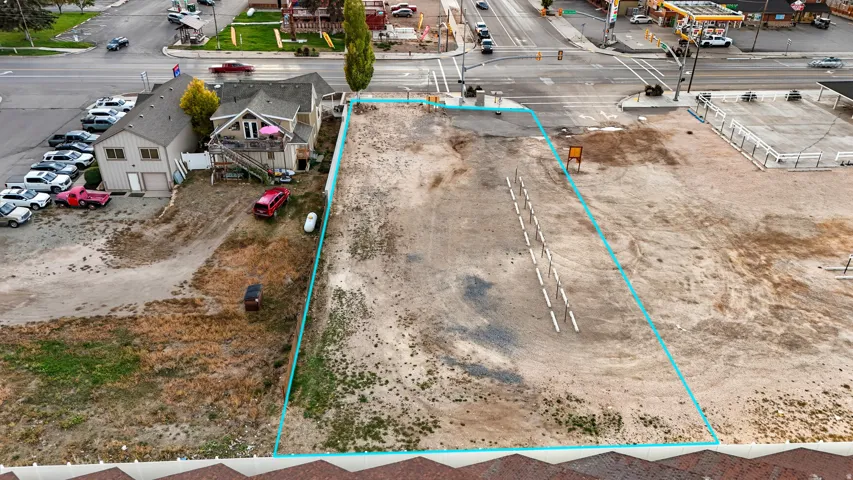 Cleared lot with direct access to a paved road, featuring a prominent corner location and visible utility poles