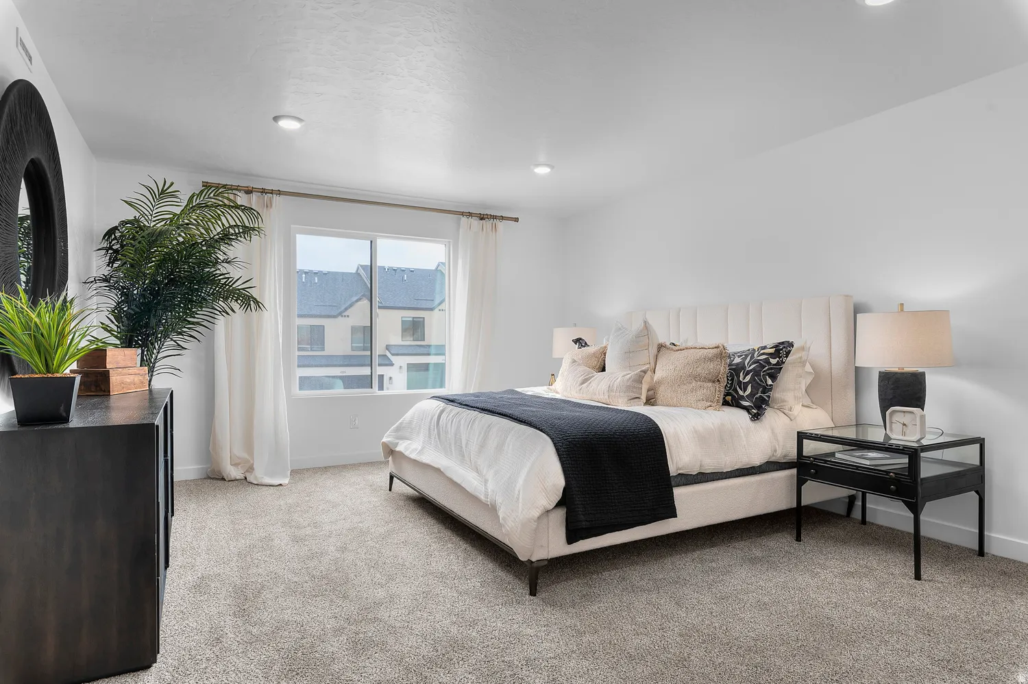 Recessed lighting, plush carpet flooring, a large window, a paneled headboard, and solid surface walls