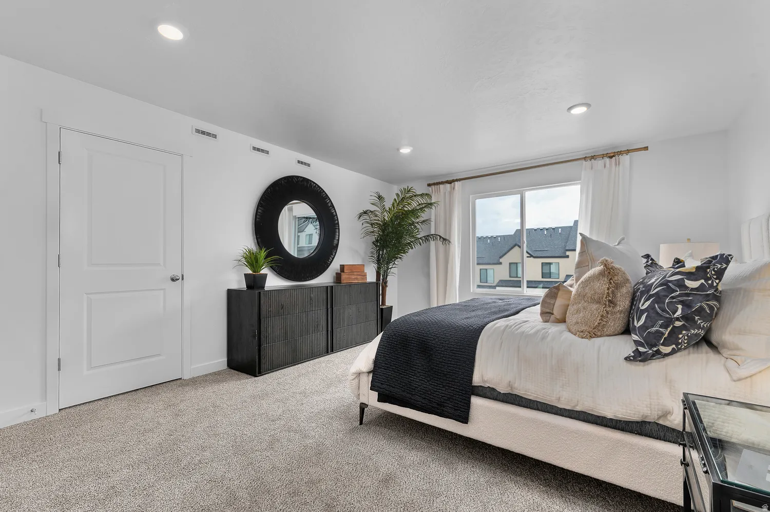 Recessed ceiling lighting, light gray carpet, window with white trim, and a white two-panel interior door