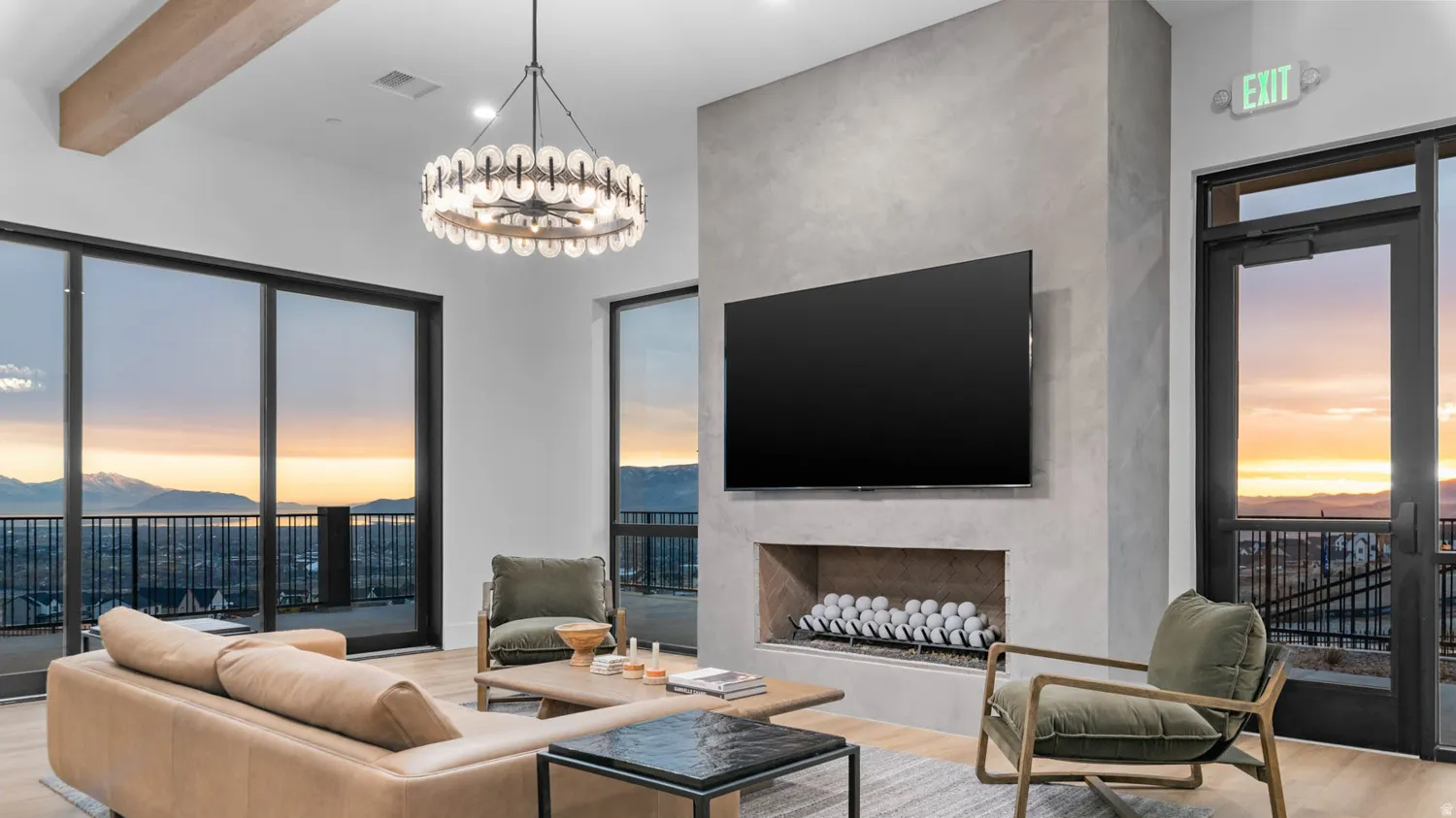 Expansive sliding glass doors, integrated linear fireplace, exposed beam ceiling, and a contemporary chandelier