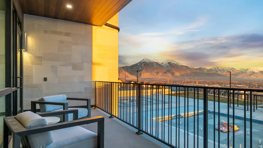Balcony with a mountain backdrop, featuring a wood-finish ceiling, mounted lighting, and a stone-clad exterior wall