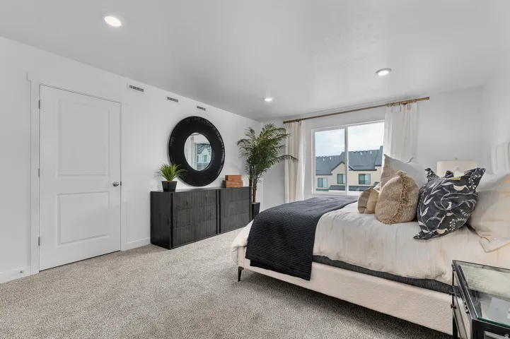 Recessed ceiling lighting, light gray carpet, window with white trim, and a white two-panel interior door