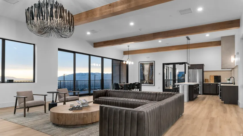Open-concept living space featuring wood-finish flooring, exposed ceiling beams, and large windows with mountain scenery