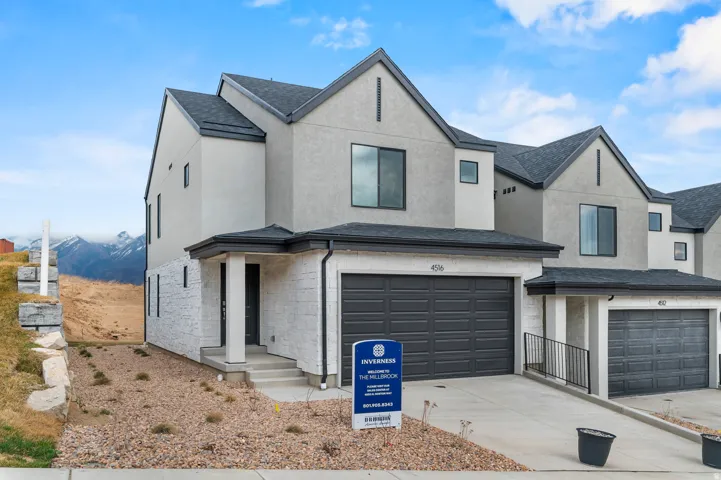 Modern architectural style featuring a light-toned stucco and white stone facade