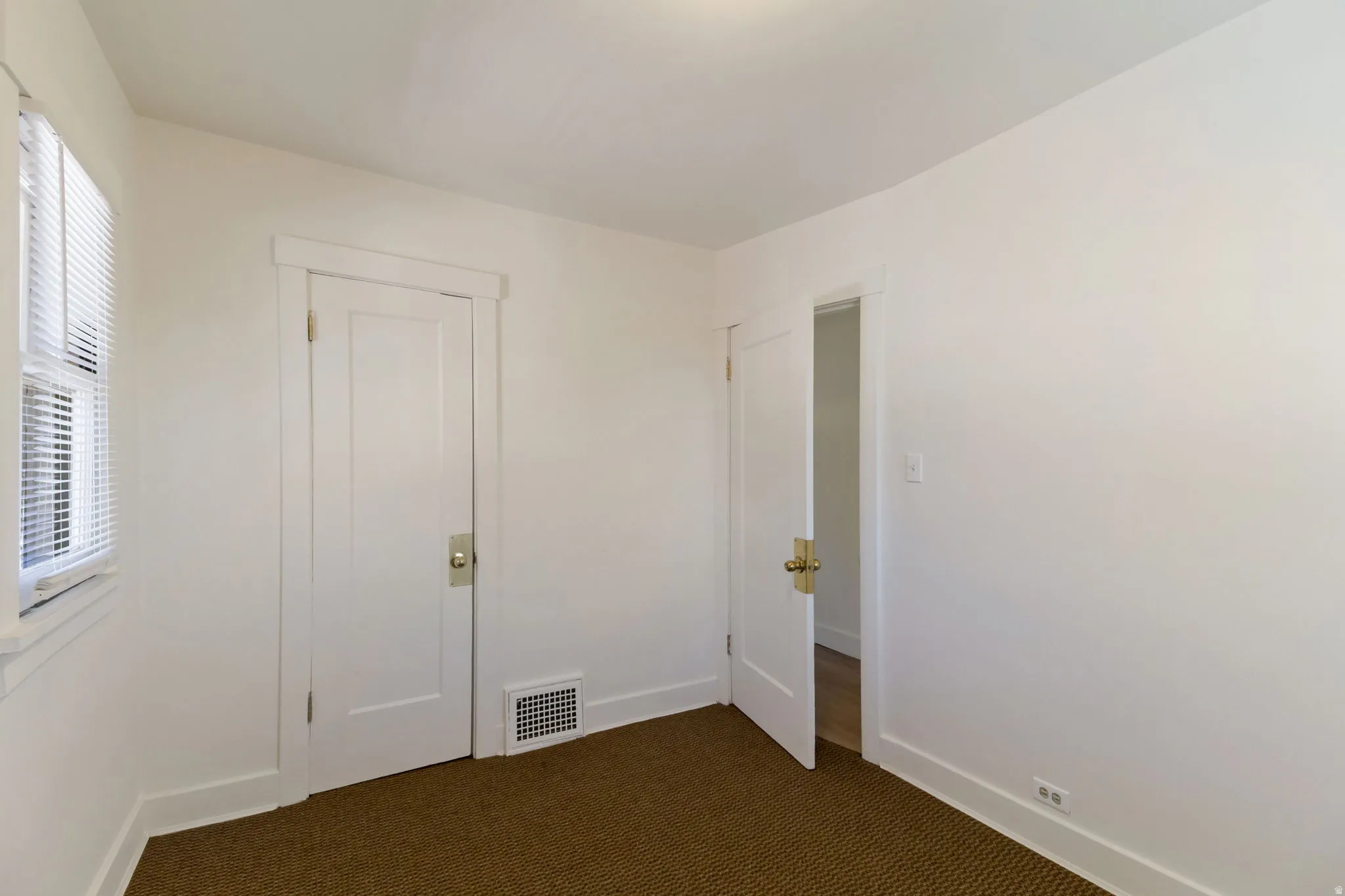 White paneled interior doors with brass hardware, white trim, and a window with blinds