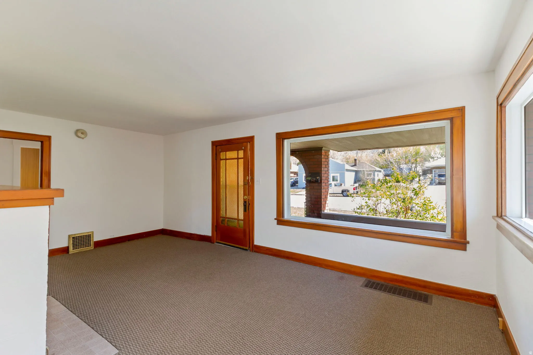 Expansive room featuring a large window, a second window, a wood-frame interior door with glass panels, and wood trim details