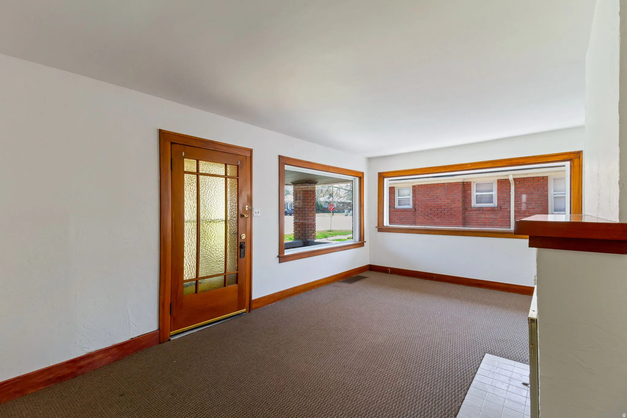 Hardwood trim and baseboards throughout, large picture windows, wood-paneled entry door with frosted glass inserts, and a built-in fireplace hearth with tile surround