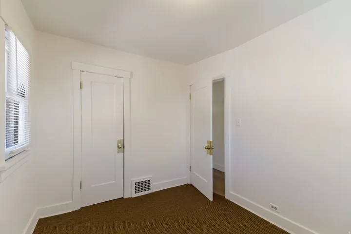 White paneled interior doors with brass hardware, white trim, and a window with blinds