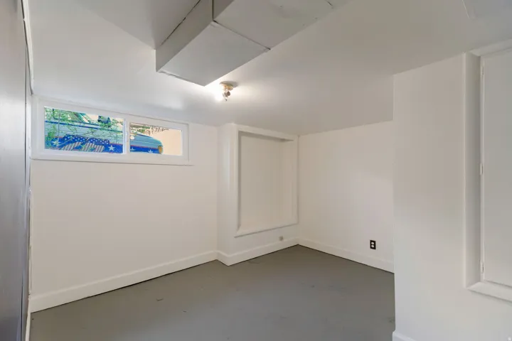Recessed window, built-in shelving, painted concrete flooring, and ceiling-mounted light fixture