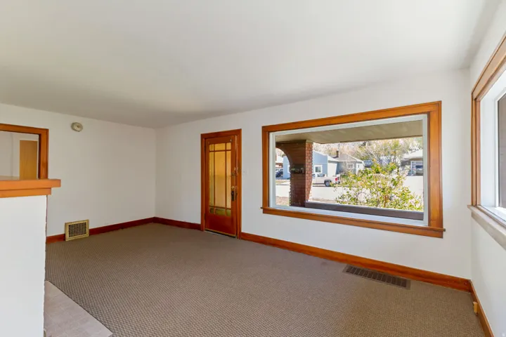 Expansive room featuring a large window, a second window, a wood-frame interior door with glass panels, and wood trim details