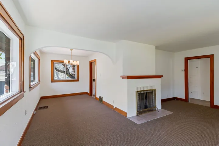 Living area with an arched entry, a fireplace featuring a tiled hearth, and multiple windows with wood trim