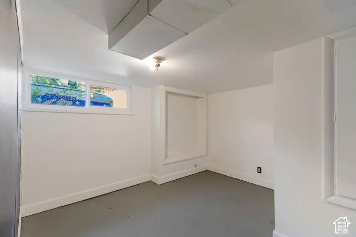 Recessed window, built-in shelving, painted concrete flooring, and ceiling-mounted light fixture