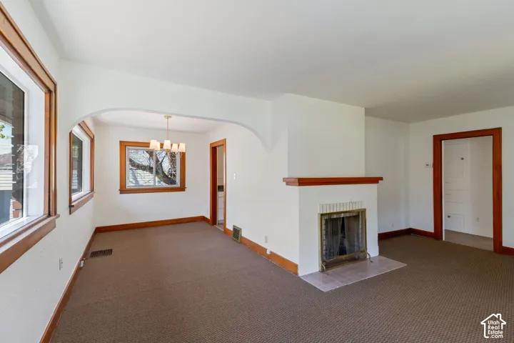 Living area with an arched entry, a fireplace featuring a tiled hearth, and multiple windows with wood trim