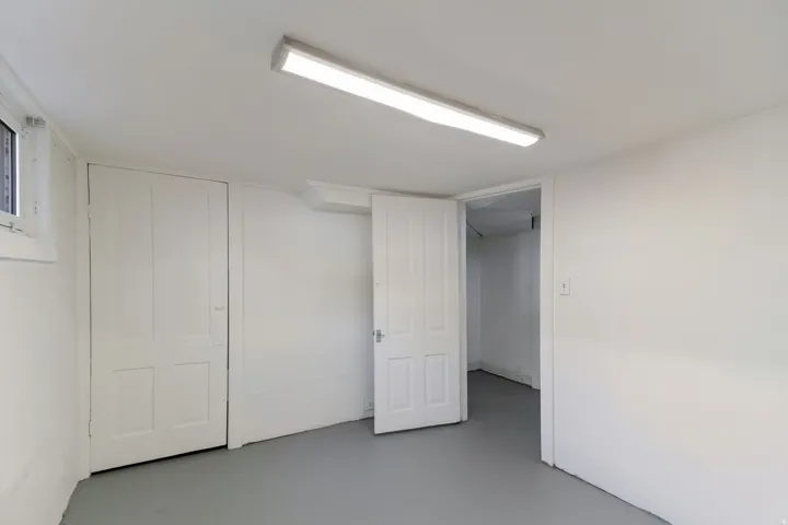 White painted walls and trim, fluorescent overhead lighting, and a single pane window