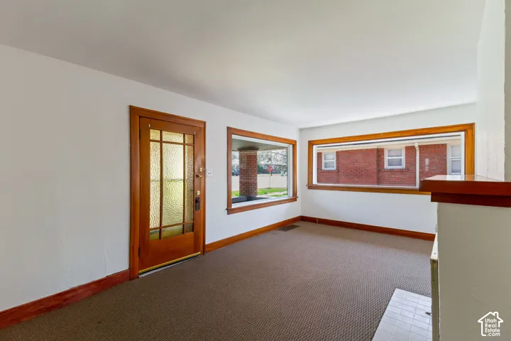 Hardwood trim and baseboards throughout, large picture windows, wood-paneled entry door with frosted glass inserts, and a built-in fireplace hearth with tile surround