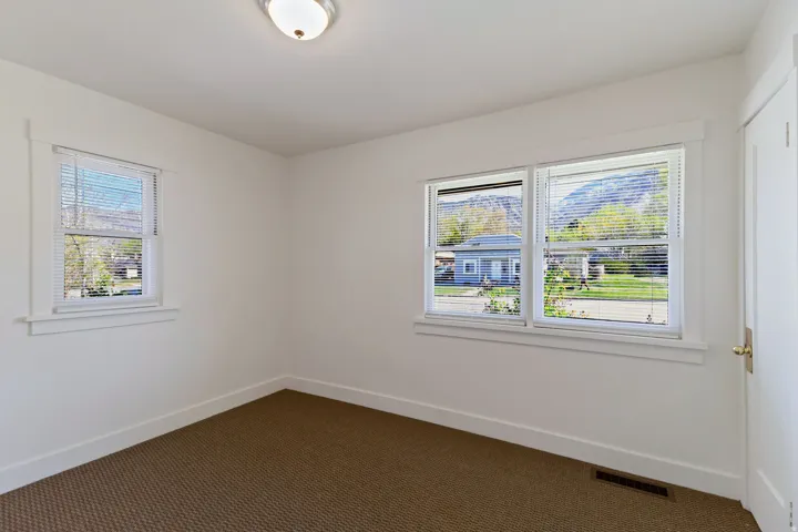 White walls, two windows, wall-to-wall carpeting, and a flush mount ceiling light