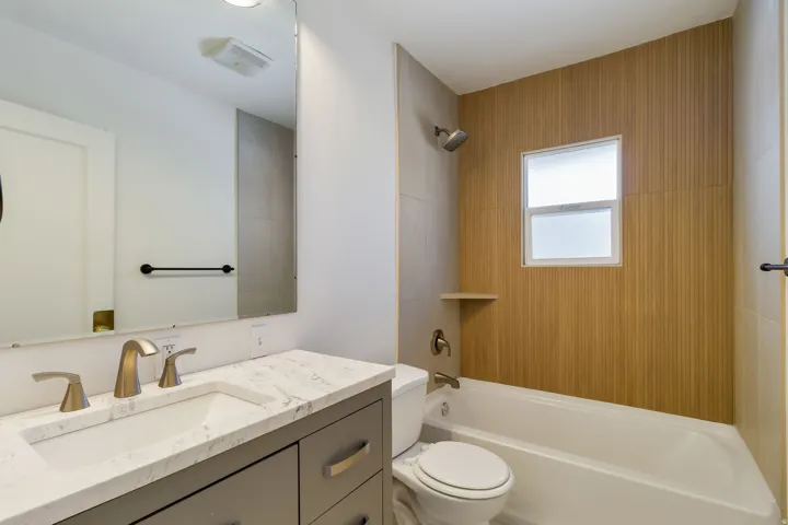 Single vanity with a light-toned countertop, integrated sink, and brushed metal fixtures