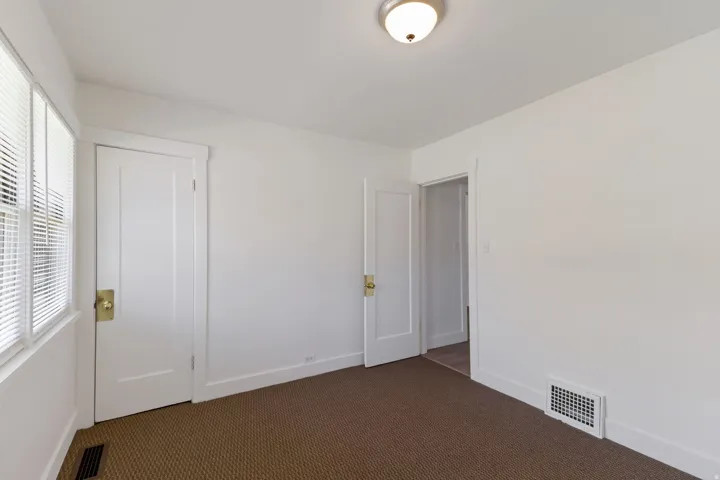 White walls, brown carpet, flush mount ceiling light, white trim, and white doors