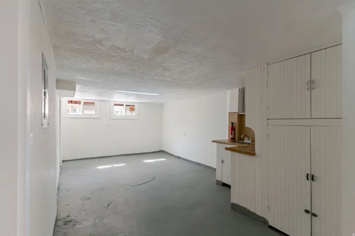 White painted walls, concrete flooring, built-in cabinetry with beadboard paneling, countertop with sink, and natural light from multiple windows