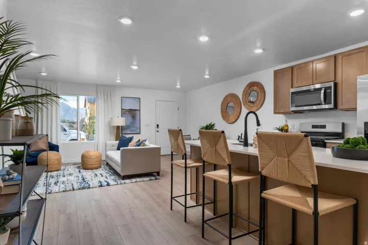 Open-concept living space featuring wood-finish flooring, recessed lighting, and a kitchen island with seating