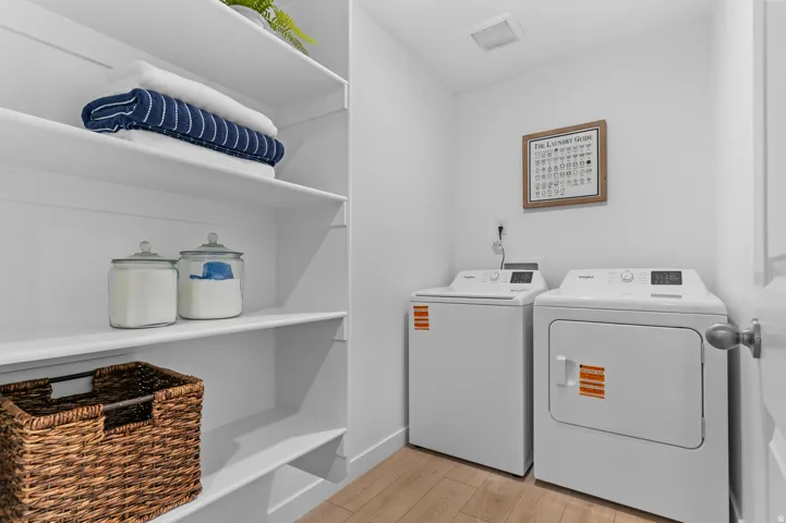 Laundry area featuring white appliances, built-in shelving, and wood-finish flooring