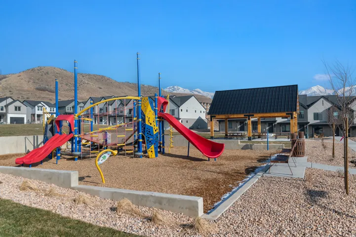 Community playground with a multi-level play structure, two slides, and wood chip surfacing
