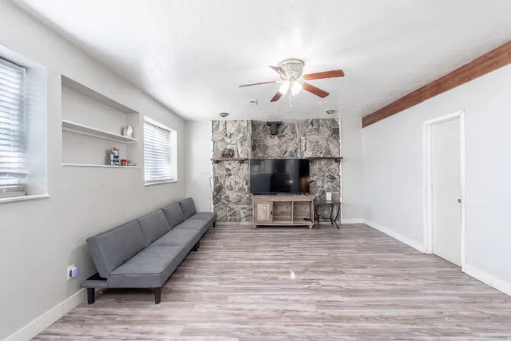 Spacious room featuring wood-finish flooring and a stone-clad fireplace