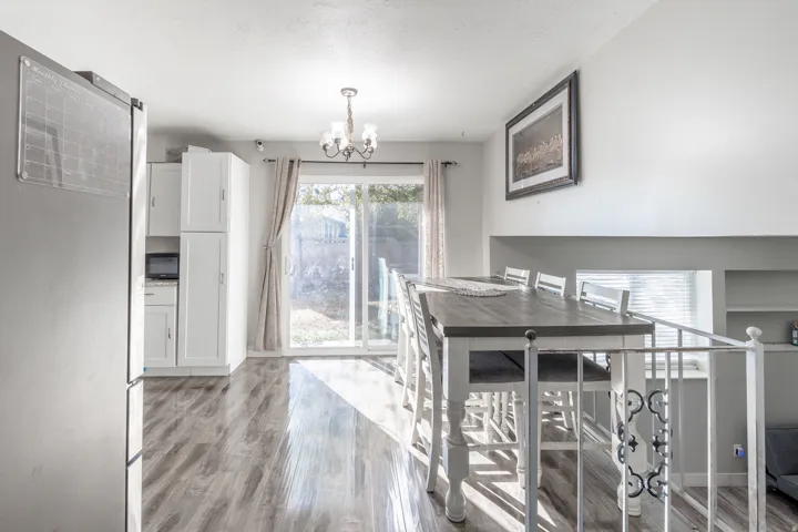 White cabinetry, wood-finish flooring, sliding glass door, overhead chandelier, and a decorative railing