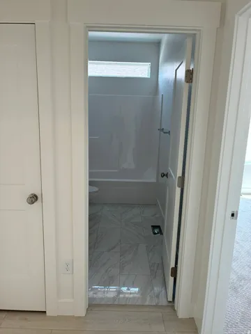 White interior doors, white trim, wood-finish flooring, and white tiled flooring