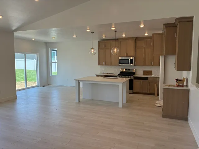 Open-concept living space with wood-finish flooring, recessed lighting, and a sliding glass door