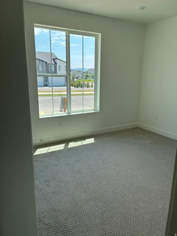 Carpeted room with a large window, recessed lighting, and white walls