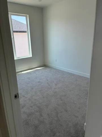 Carpeted room with a single window and white walls