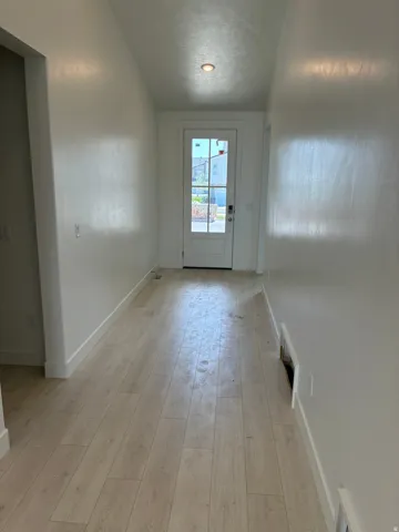 Wood-finish flooring, recessed ceiling lighting, and a white paneled door with windowpanes