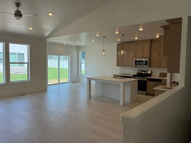 Open-concept living area with light wood-finish flooring, recessed lighting, and a ceiling fan