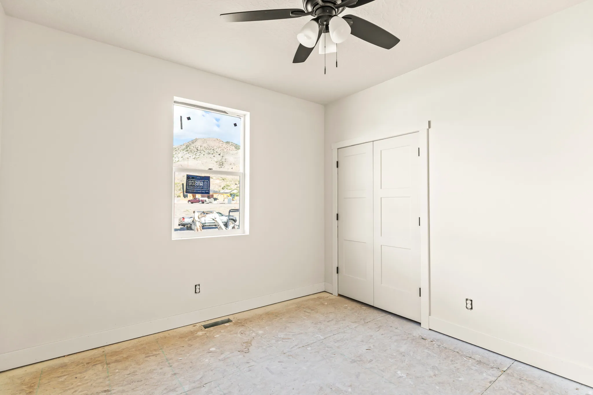 Room featuring a window, ceiling fan, and bi-fold closet doors