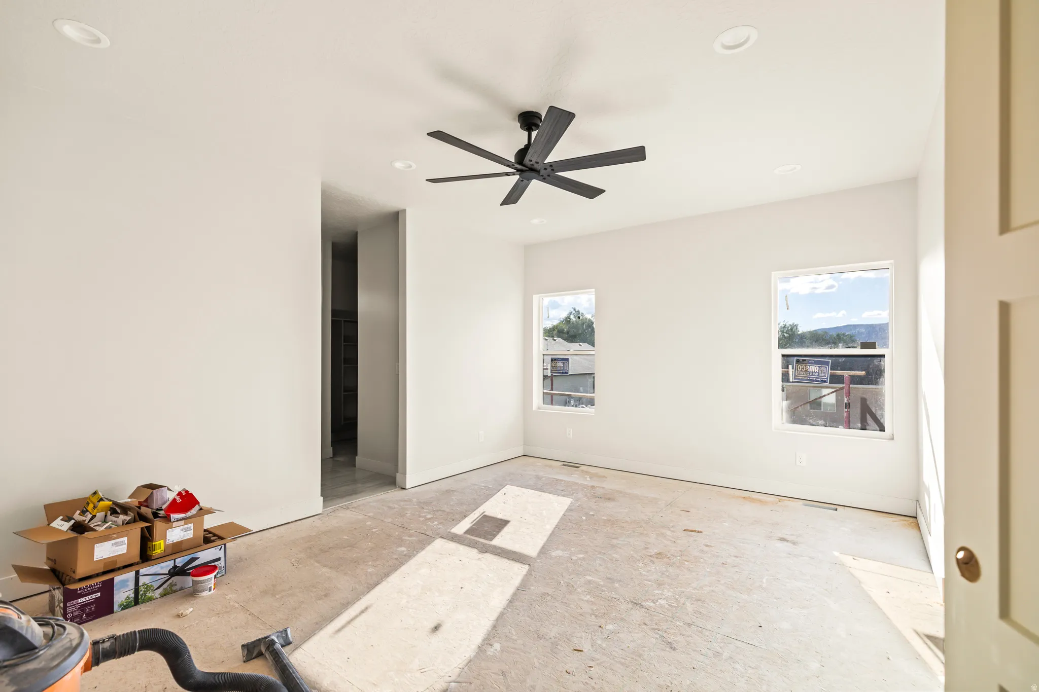 Recessed ceiling lighting, ceiling fan, two windows, and a doorway