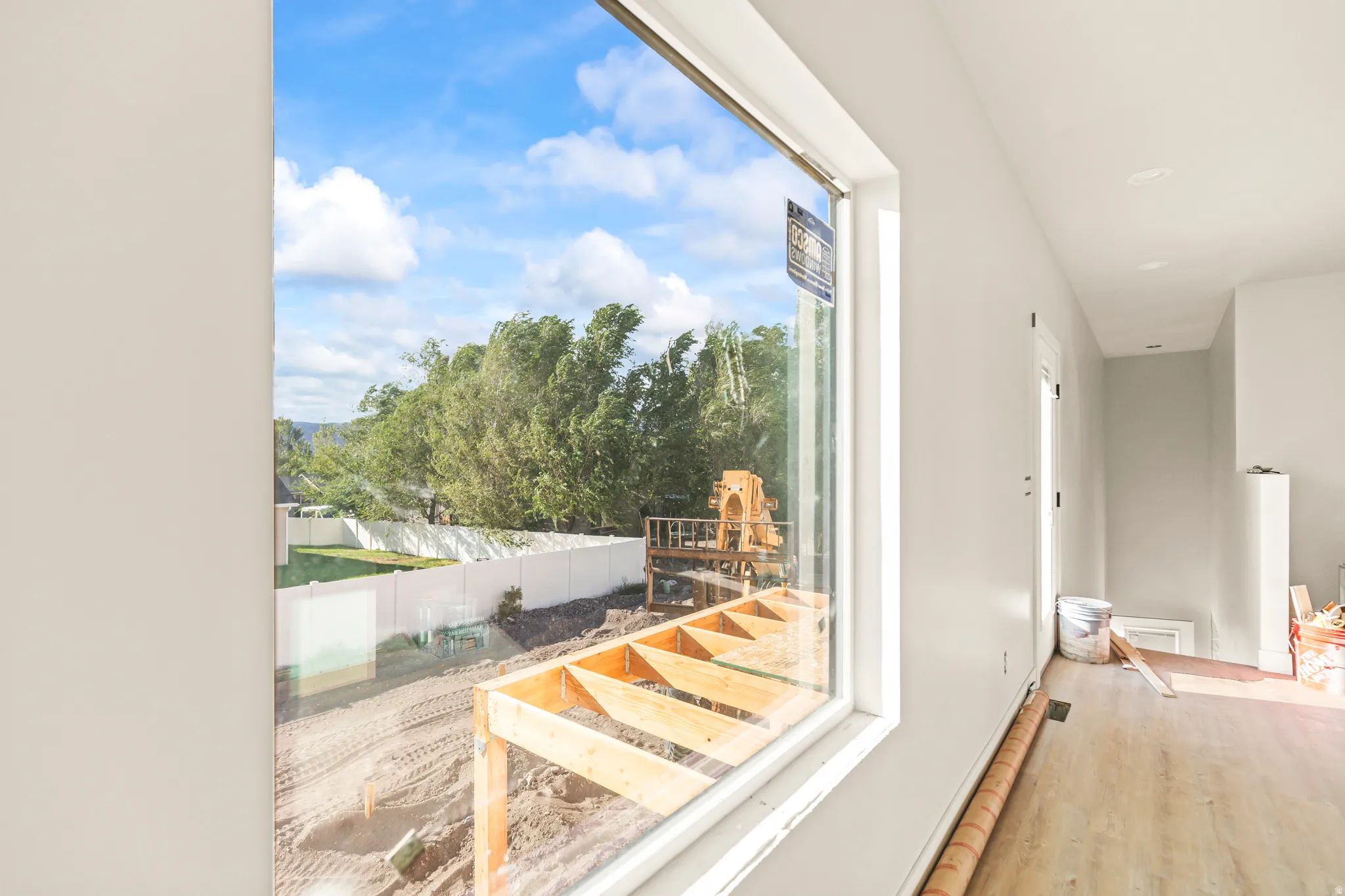 Large format window, light gray wall finish, recessed ceiling lighting, wood-finish flooring, white privacy fence