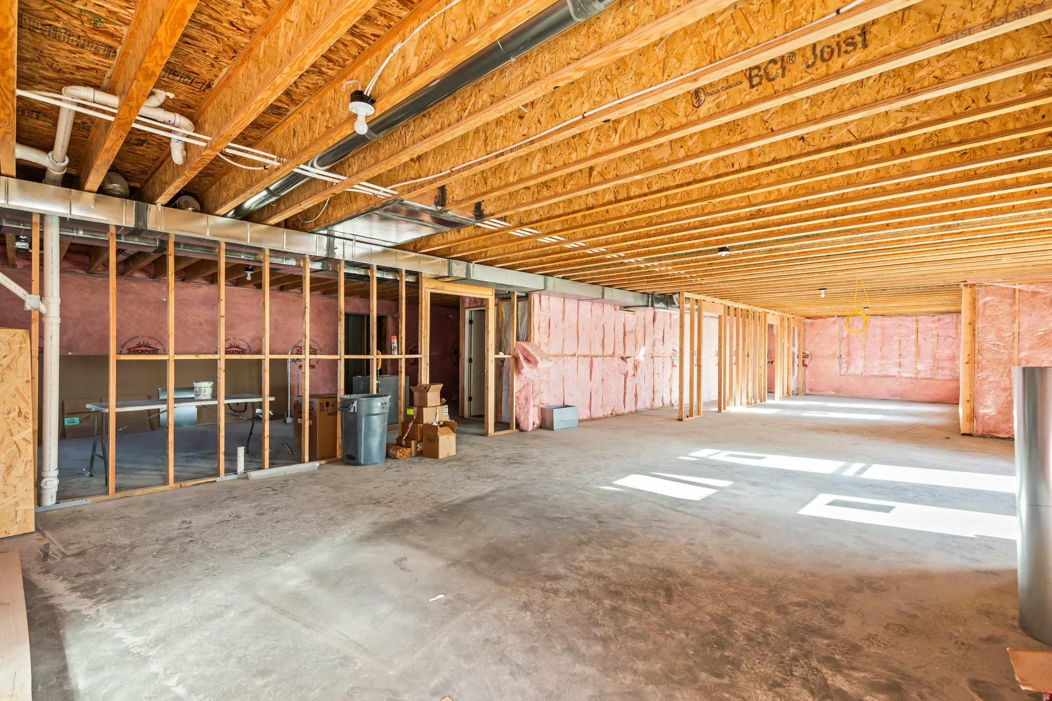 Open unfinished basement with exposed joists, concrete flooring, and insulated walls