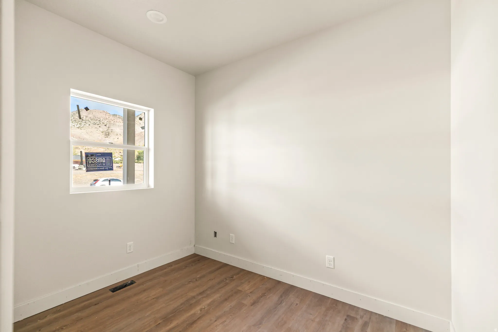 Light-colored walls, recessed ceiling lighting, a window with a mountain backdrop, and wood-finish flooring