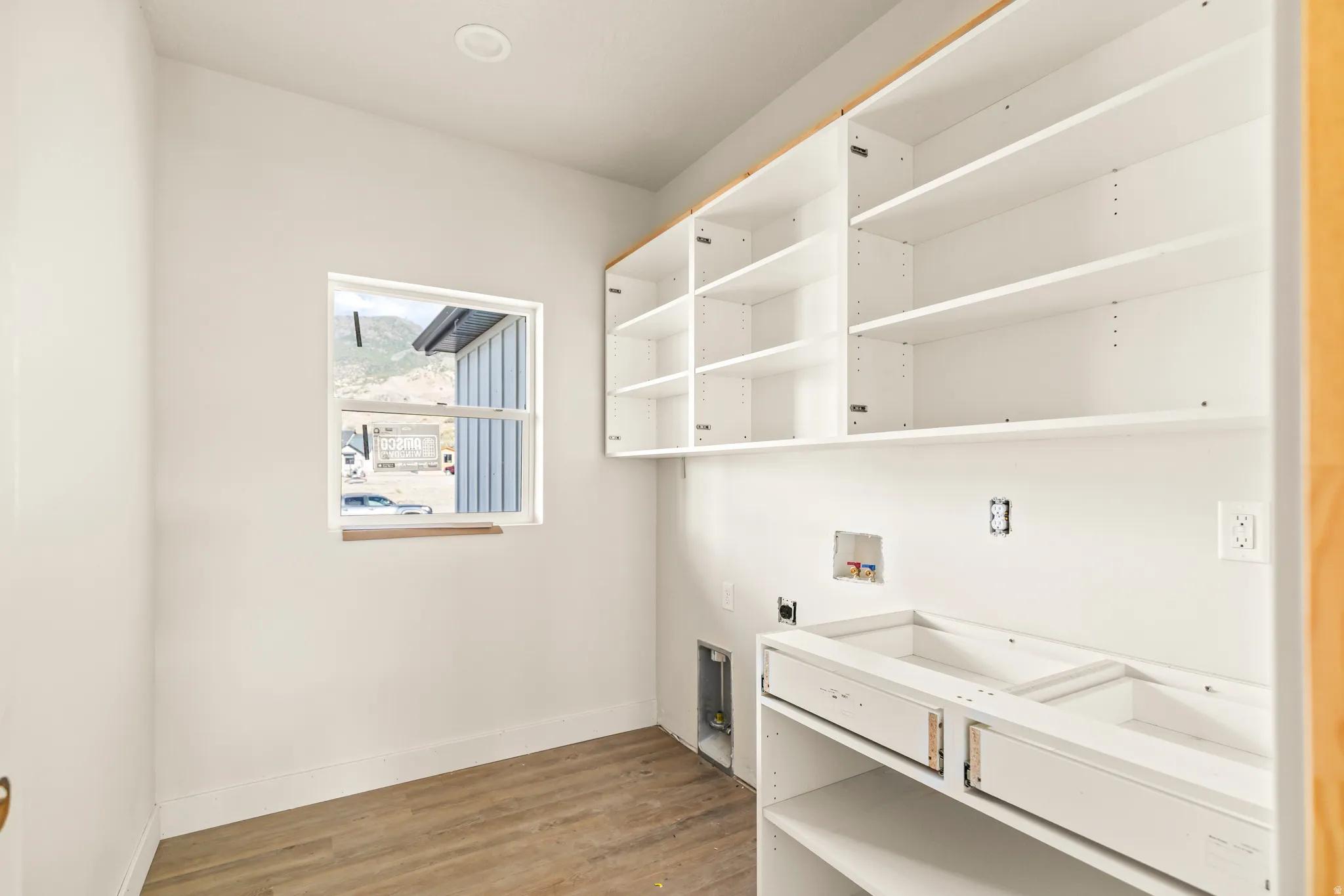 White cabinetry with open shelving, recessed lighting, wood-finish flooring, and a window