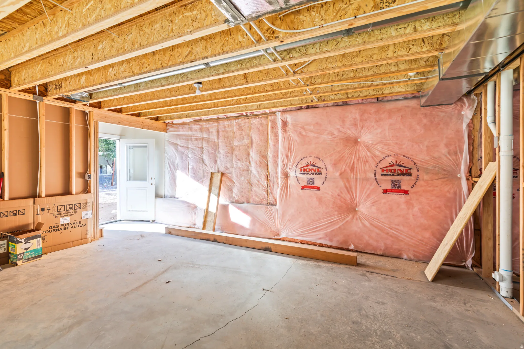Unfinished lower level featuring exposed wood joists, concrete flooring, and insulated wall framing