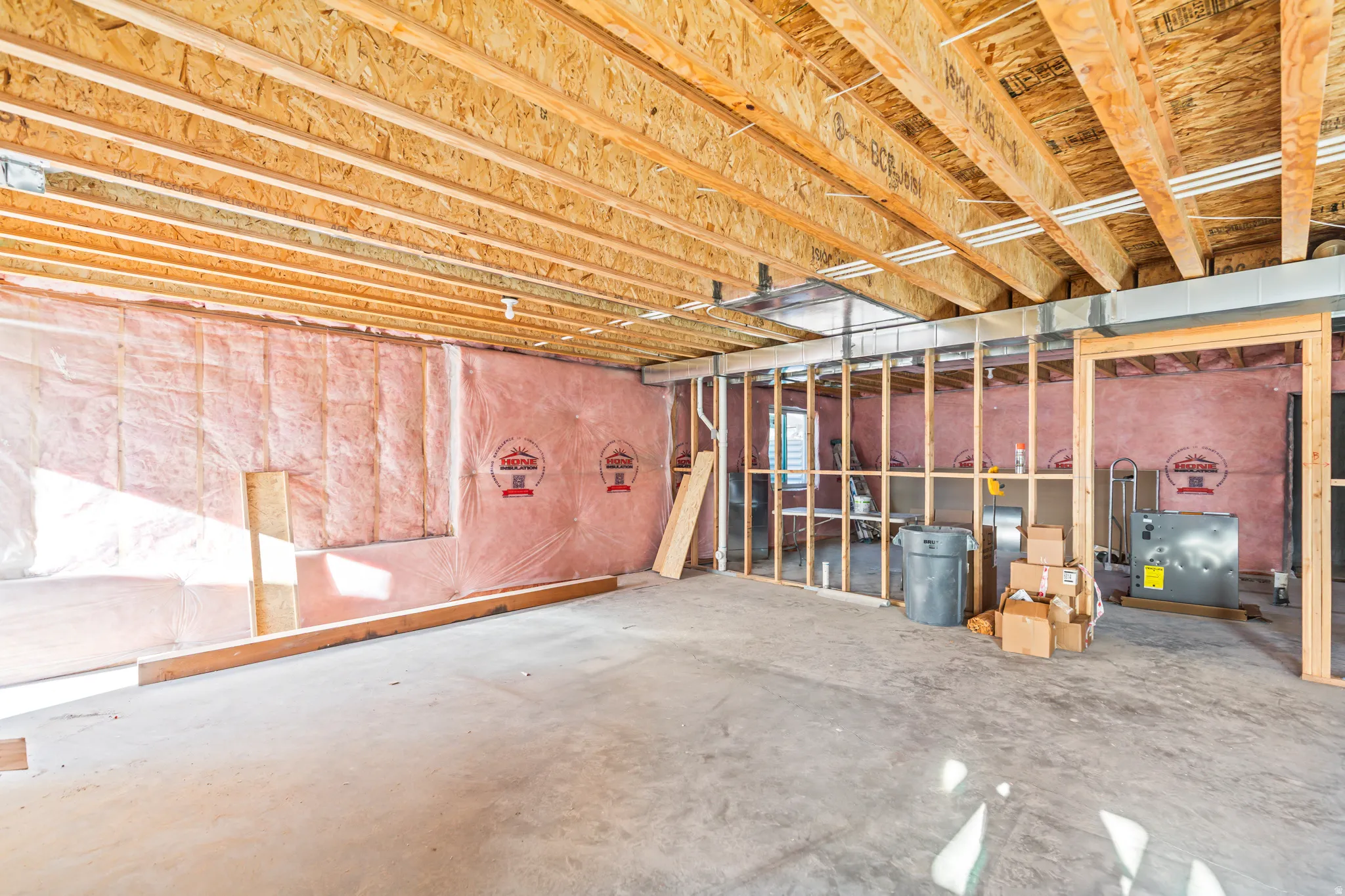 Unfinished lower level featuring exposed wood joists, concrete flooring, and partial wall framing