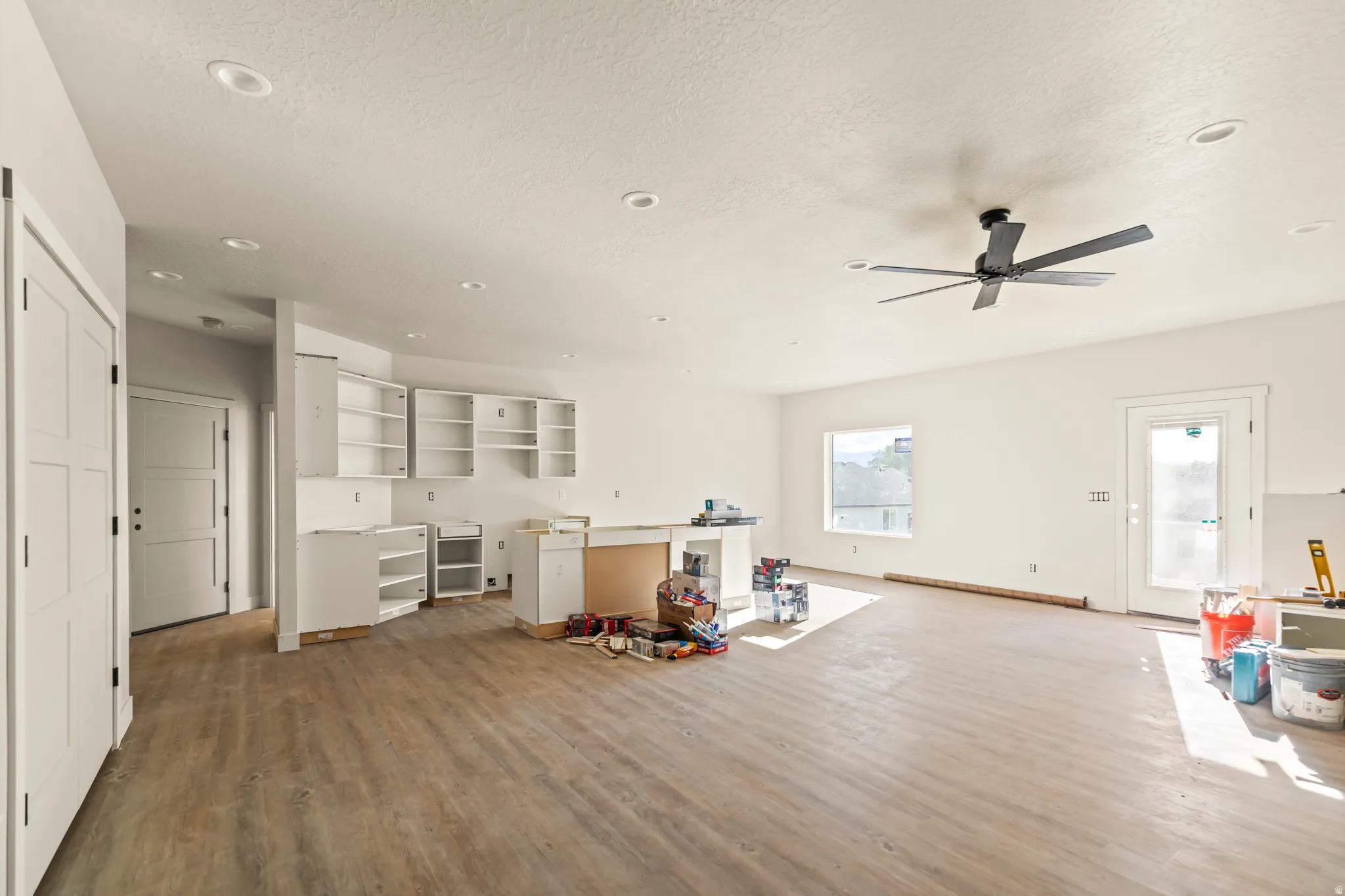 Open-concept living space with wood-finish flooring, recessed lighting, and a ceiling fan