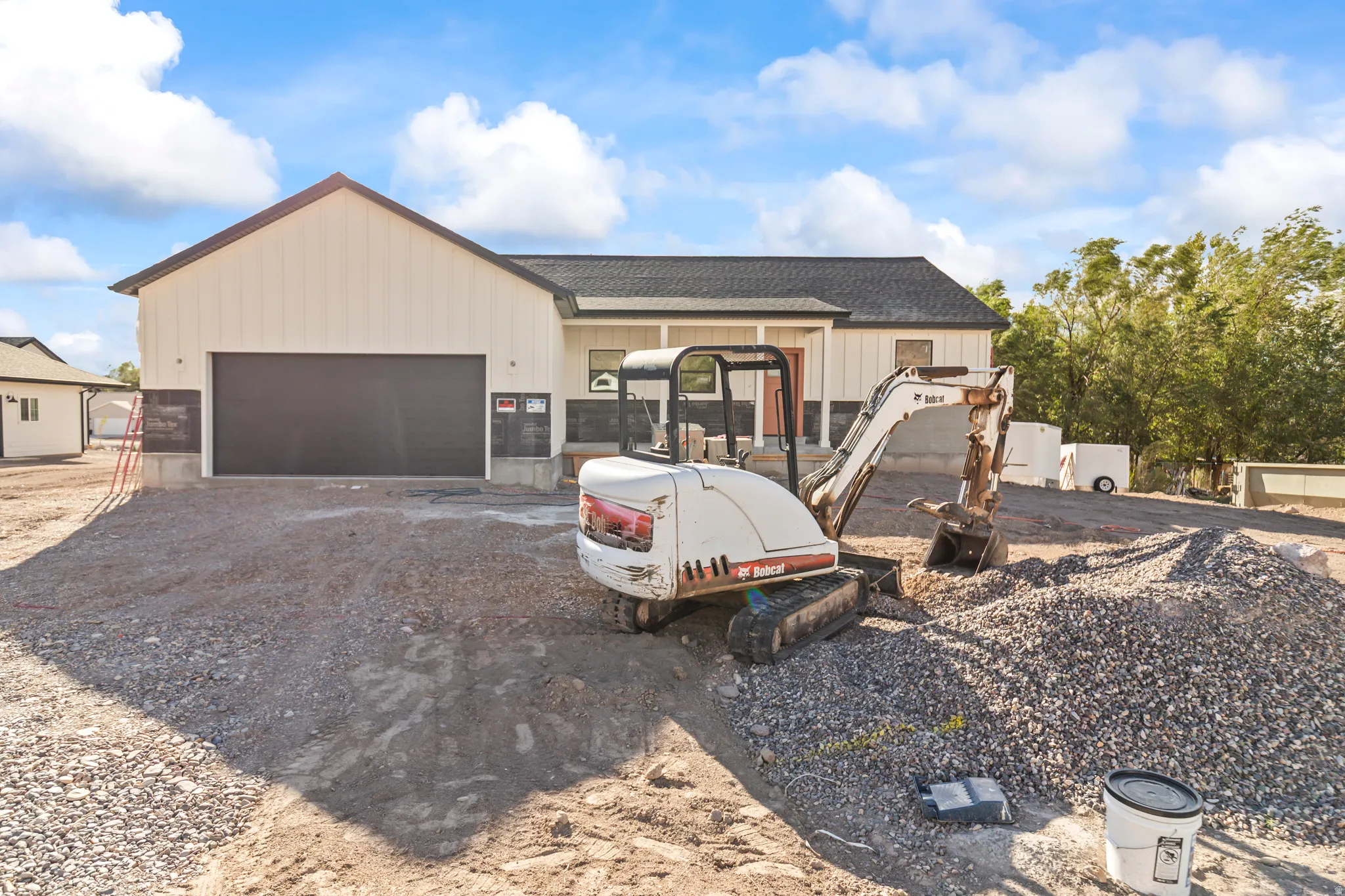 New construction residence featuring a black asphalt shingle roof, light-colored vertical siding, and an attached two-car garage with a dark door