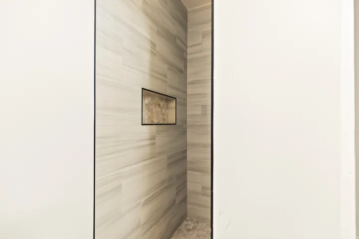 Tiled shower enclosure featuring a recessed niche and pebble-style flooring